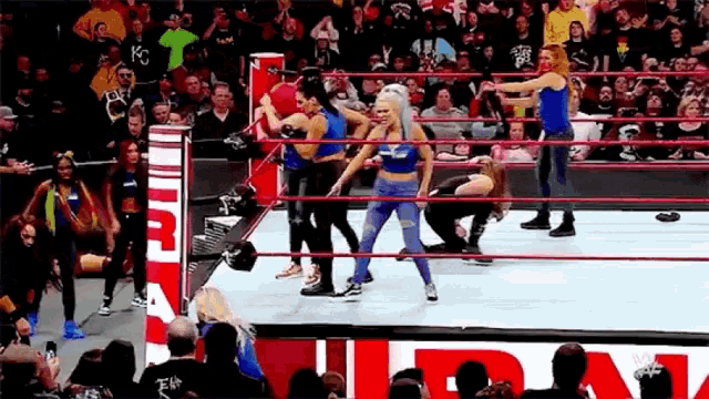 a group of women are wrestling in a wrestling ring while a crowd watches .