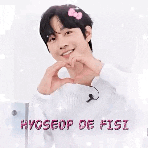 a young man is making a heart shape with his hands while wearing a hello kitty headband .