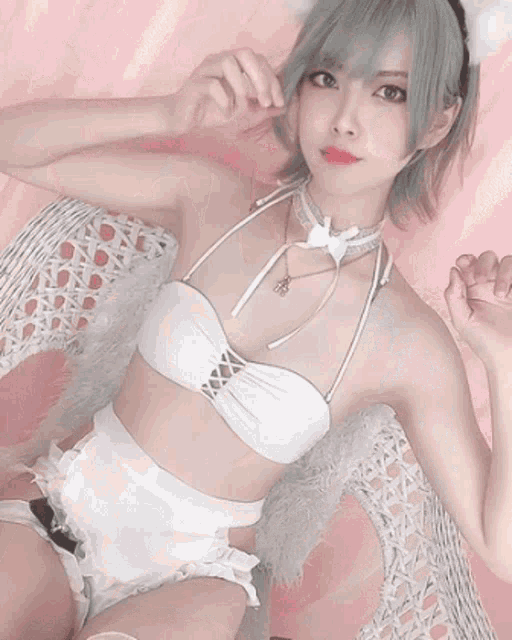 a woman in a white bikini is smiling and giving a peace sign