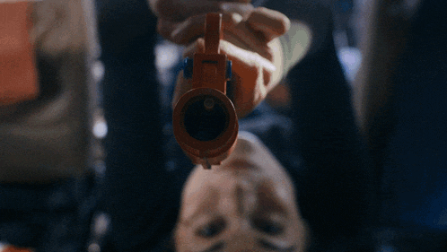 a person laying on their back holding an orange toy gun