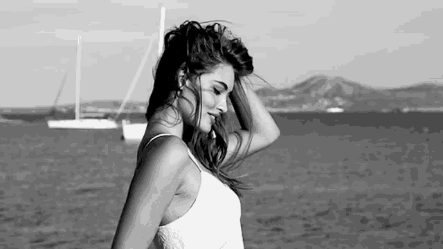 a black and white photo of a woman standing in front of a body of water .