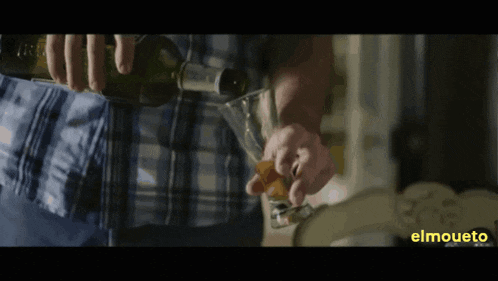 a man is pouring a drink from a bottle into a glass with elmouto written on the bottom