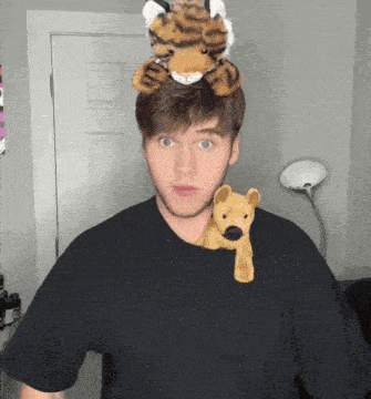 a man with a stuffed tiger on his head and a stuffed dog on his shoulder