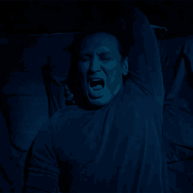 a man laying in bed with his mouth open