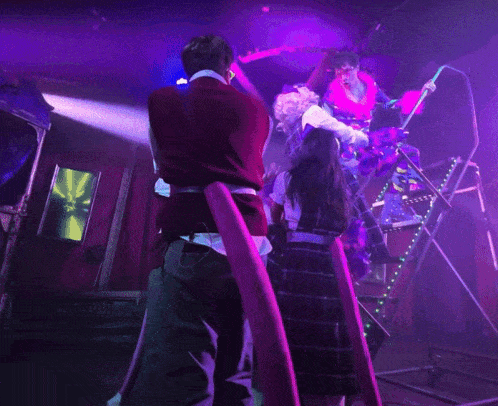 a group of people standing on a stage with purple lights