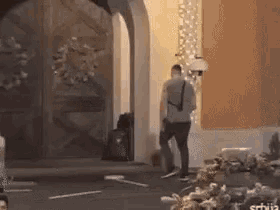 a man standing in front of a building with a suitcase .