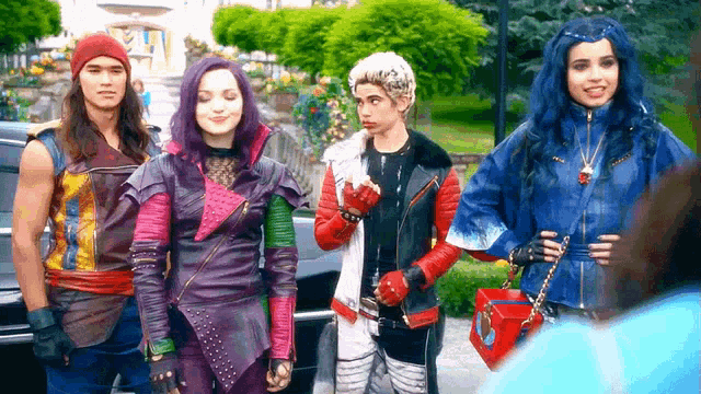 a group of descendants characters are standing next to each other in front of a car .