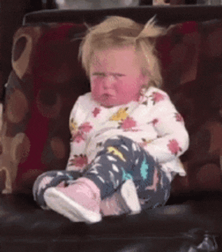 a little girl is sitting on a couch with her legs crossed .
