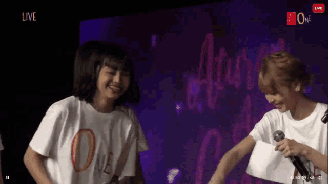 a couple of girls standing next to each other on a stage with the word live in the upper right corner