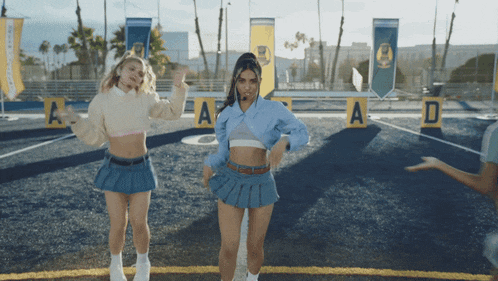two girls are dancing on a field with a and d signs