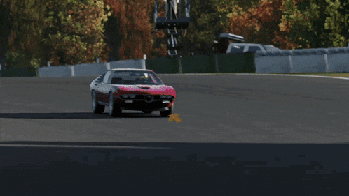 a red car is driving down a race track with a sign that says ferrari on it