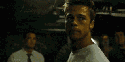 a man in a white shirt is standing in front of a group of people .