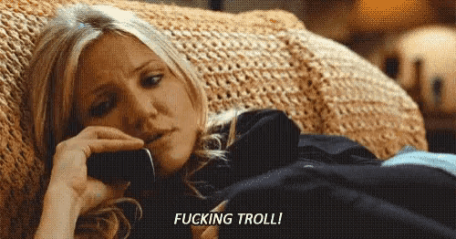 a woman is laying on a couch talking on a cell phone and saying fucking troll !