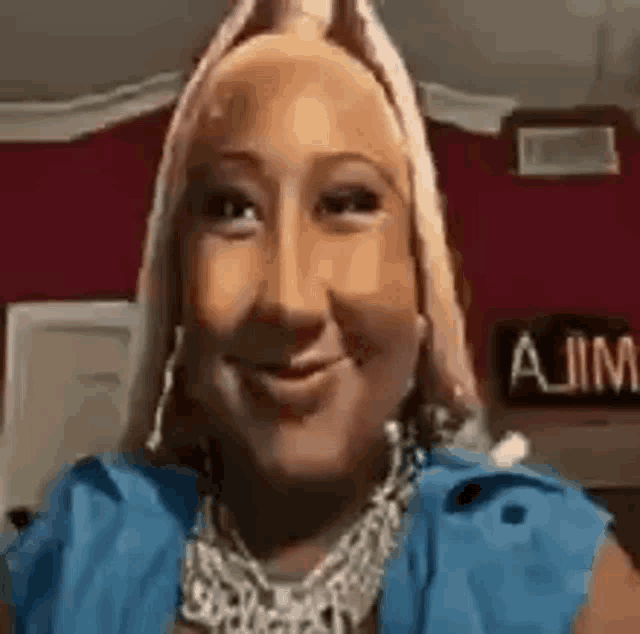 a woman wearing a blue jacket and a necklace is smiling .