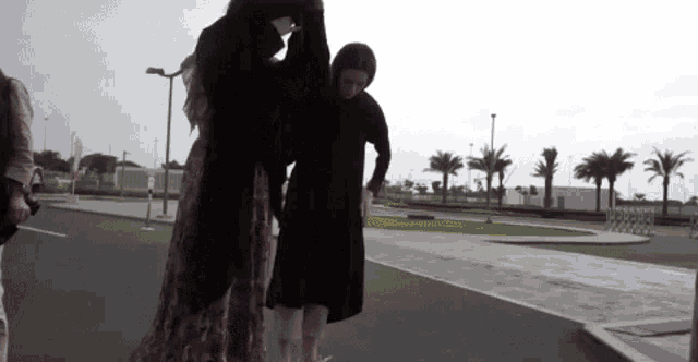 a woman in a hijab is helping another woman walk down the street
