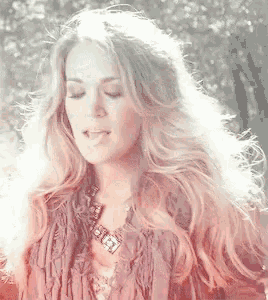 a woman with long blonde hair is wearing a fringed jacket and a necklace