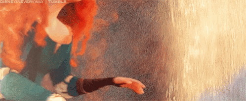 a woman with red hair is standing in front of a wall holding her hand out .