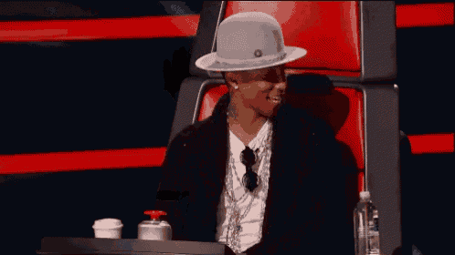 a man wearing a hat sits in a red chair