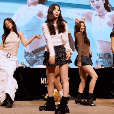 a group of girls are dancing in front of a sign that says mu on it