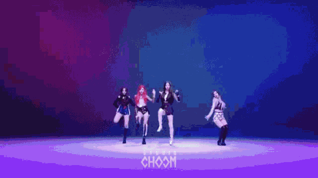 a group of girls are dancing on a stage in front of a purple background .