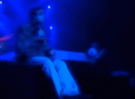 a blurry photo of a man sitting on a stage with a microphone