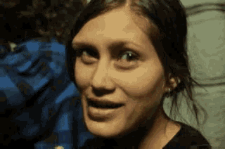 a close up of a woman 's face with a blue plaid shirt behind her