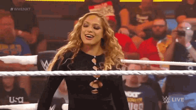 a woman is standing in a wrestling ring and smiling