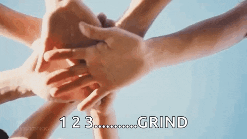 a group of people are putting their hands together in a circle against a blue sky .