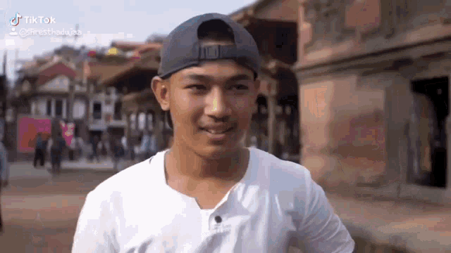 a man wearing a hat and a white shirt is smiling