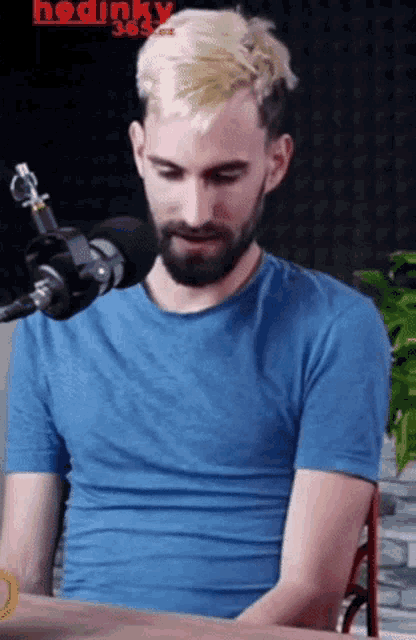 a man in a blue shirt is sitting in front of a microphone with the word hodinky 365.cz on the bottom right