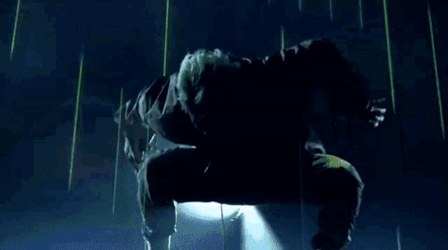 a man in a purple jacket and blue pants is kneeling down in a dark room
