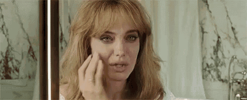 a woman is applying makeup to her face in front of a mirror in a bathroom .
