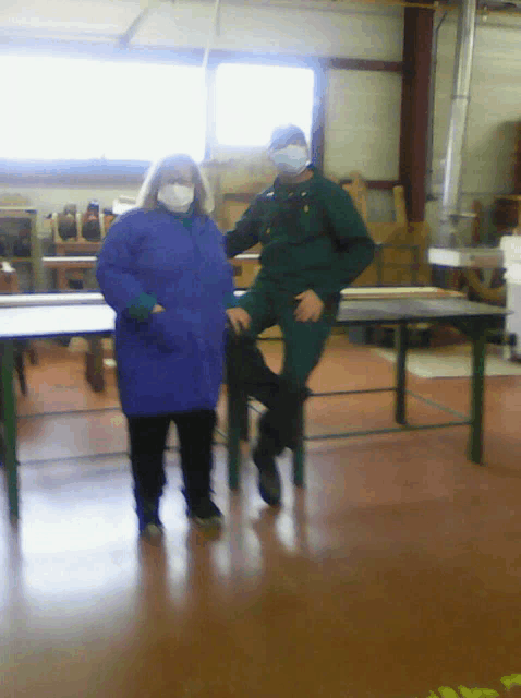 a man and a woman wearing face masks are standing next to each other in a room