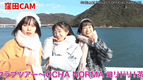 three girls are standing next to each other in front of a body of water with cam written on the bottom right