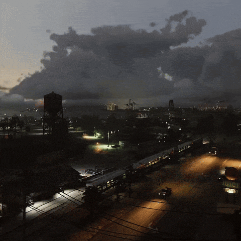 an aerial view of a city at night with a water tower in the distance