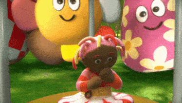 a doll with pink hair is sitting in front of a yellow flower