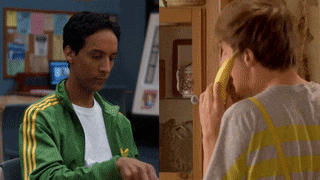 a man in a green jacket is eating a banana next to another man