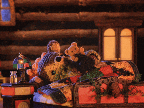 a teddy bear is laying on a bed with a blanket and a lamp