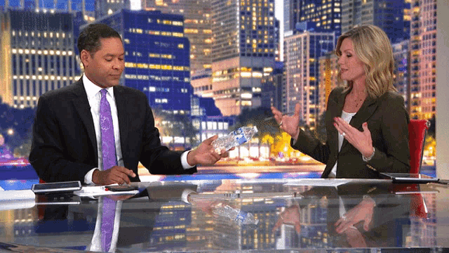a man in a suit and tie holds a bottle of water in front of a woman