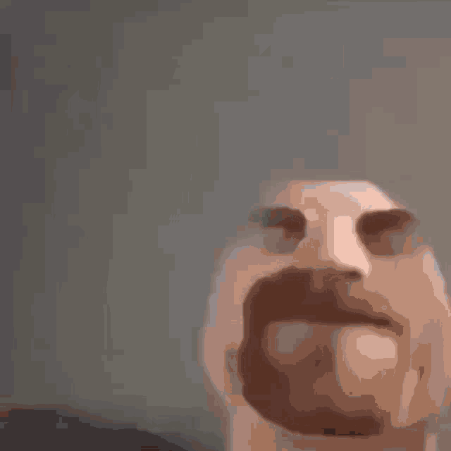 a close up of a man 's face with a mustache behind a glass .