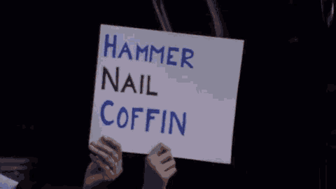 a person is holding a sign that says hammer nail coffin