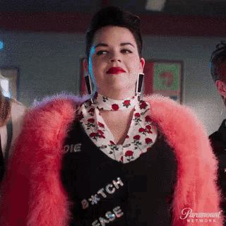 a woman wearing a pink fur coat and a shirt that says " bitch face "