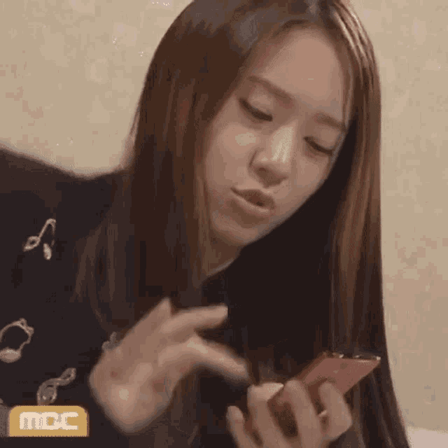 a woman with long hair is holding a red cell phone in her hands .