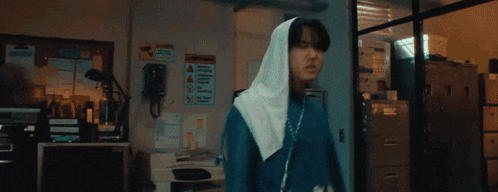 a woman wearing a white hijab is standing in front of a monitor .