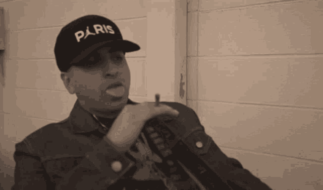 a man wearing a hat that says paris is smoking a cigarette