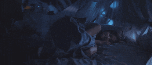 a person is sleeping under a canopy with a blue blanket