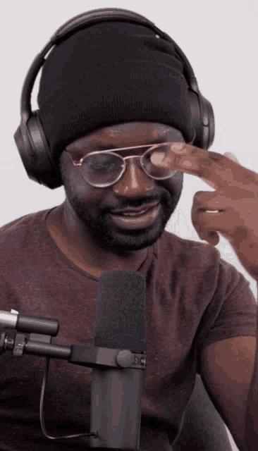 a man wearing headphones and glasses is pointing at his eye