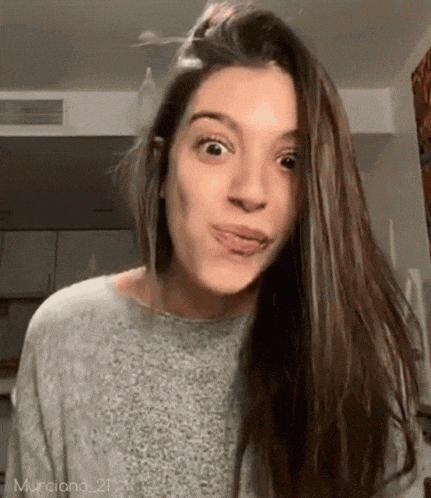 a woman with long hair is making a funny face with her tongue out .