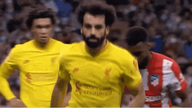 a soccer player in a yellow jersey is running on a field .