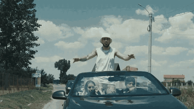 a man in a white hat is standing in the back of a car